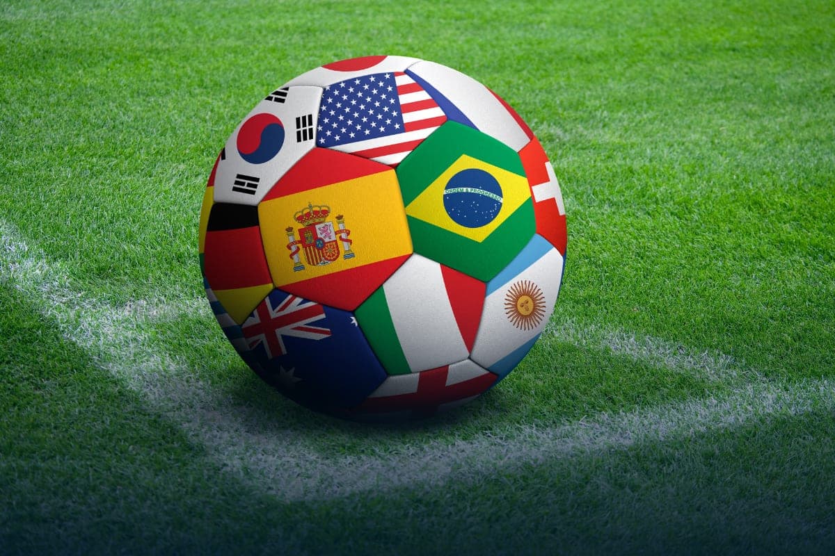 A football patterned with the flags of many nations, resting on a pitch marking