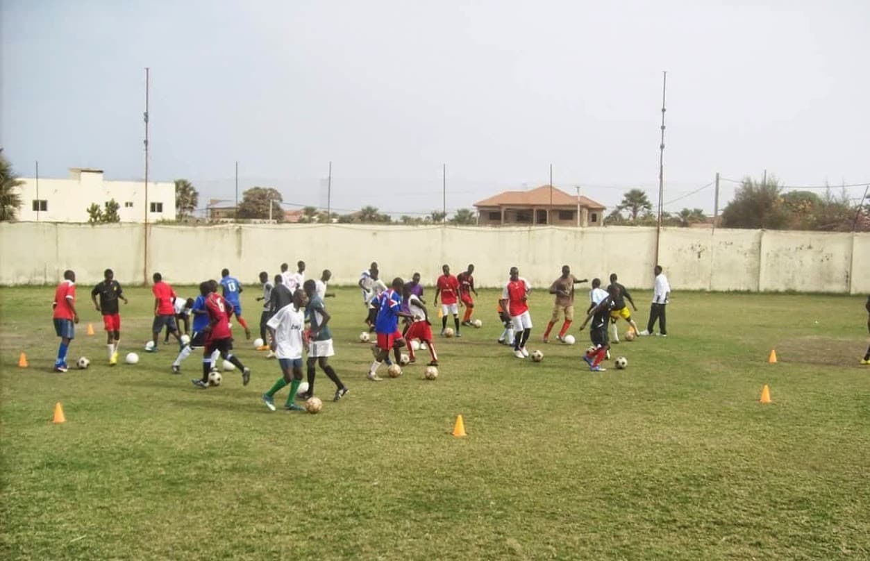 A youth coaching session in progress on a grass pitch at the AsiaEurope Football Academy in The Gambia